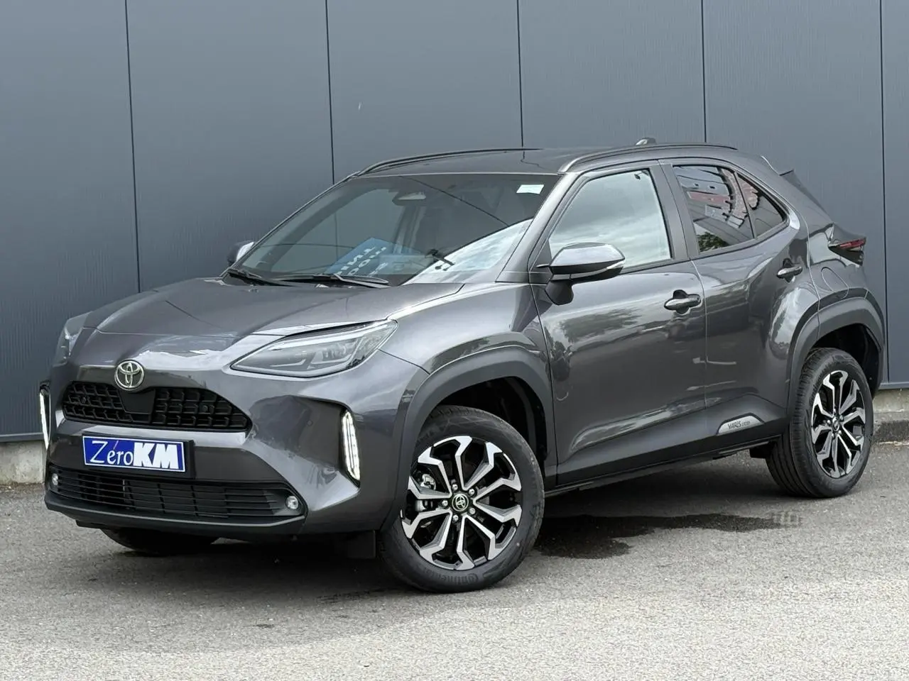 Toyota Yaris Cross gris Atlas vue 3/4 avant droit, avec jantes alliage noires et détails noirs contrastants.