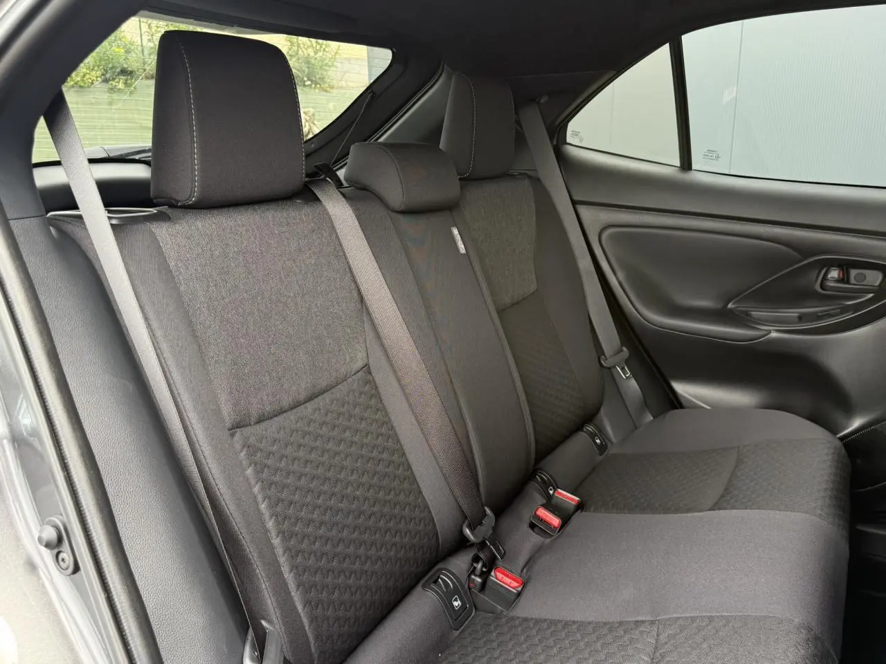 Vue intérieure côté droit des sièges arrière gris foncé de la Toyota Yaris Cross 1.5 Hybrid 2026 avec ceinture et appuie-tête.