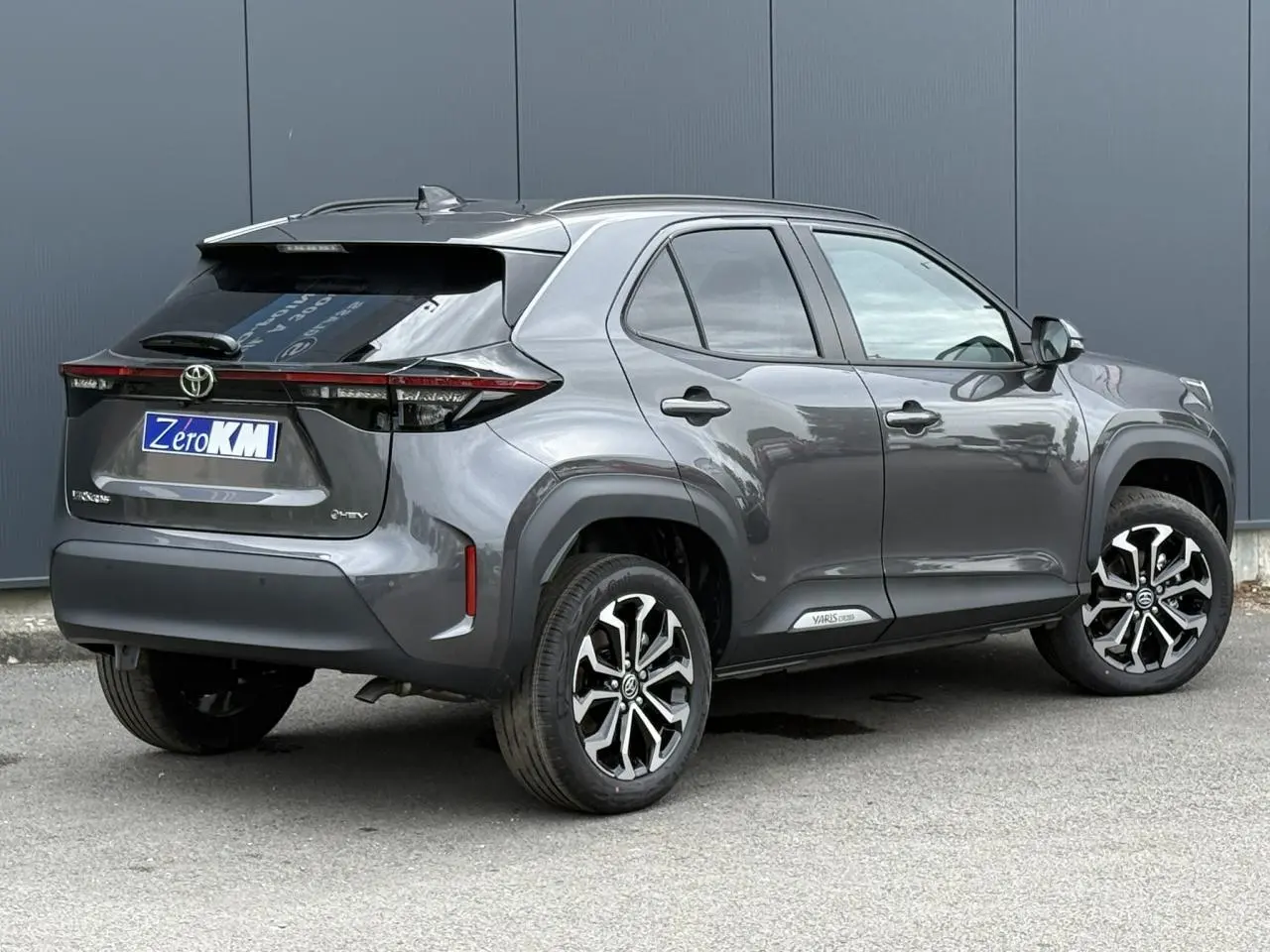 Toyota Yaris Cross gris Atlas en 3/4 arrière droit, avec jantes alliage noires et toit noir contrasté.