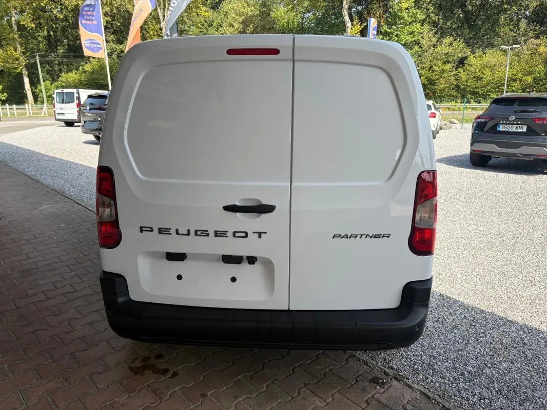 Vue arrière d’un Peugeot Partner blanc, fourgon utilitaire avec portes battantes et feux arrière verticaux.