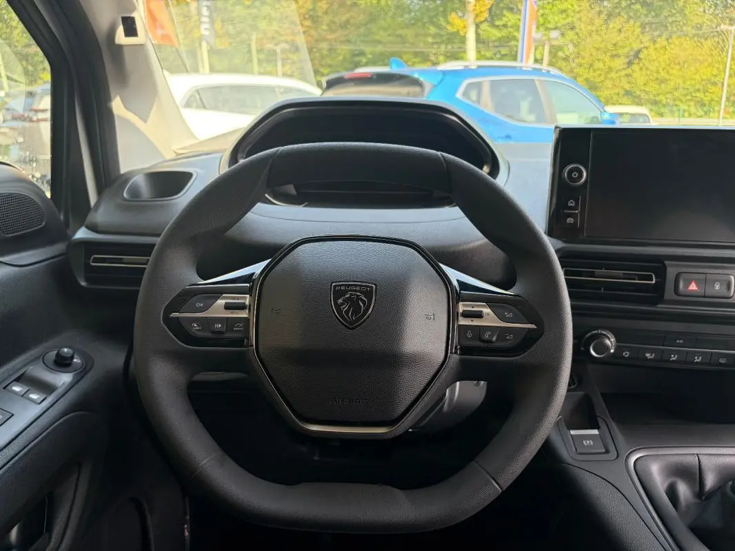 Vue intérieure centrée sur le volant cuir multifonctions noir du Peugeot Partner 2026 avec tableau de bord et écran tactile.