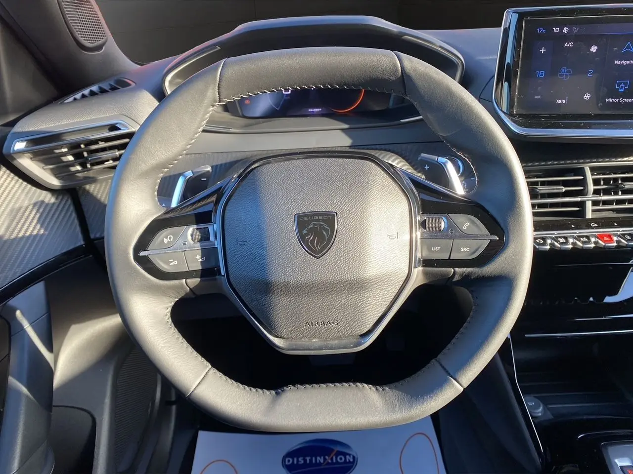 Vue rapprochée du volant cuir noir du Peugeot 2008 2024 avec commandes intégrées et tableau de bord numérique.