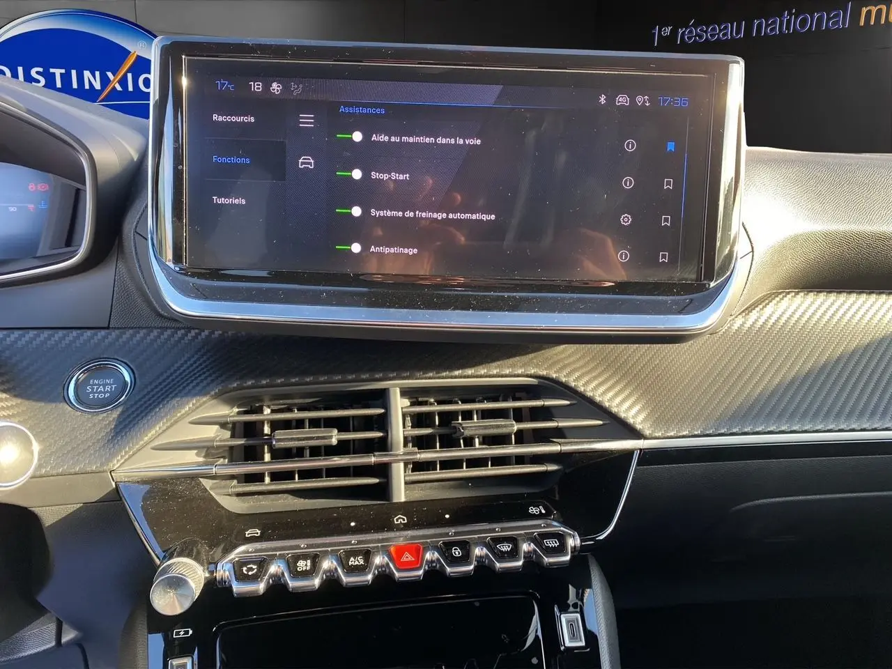 Tableau de bord de Peugeot 2008 2024 avec écran tactile affichant les aides à la conduite, finition noire et détails carbone.