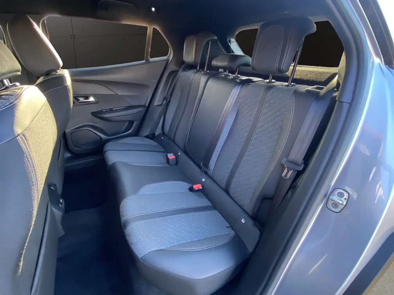 Vue intérieure arrière droite des sièges en tissu et cuir noir du Peugeot 2008 gris Artense 2024, version diesel automatique.