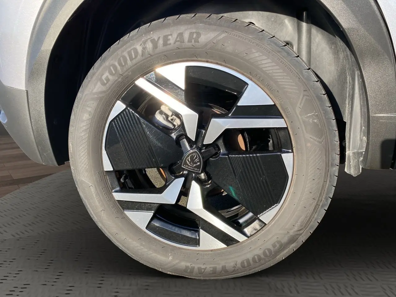 Gros plan sur la roue avant gauche du Peugeot 2008 gris Artense avec jante alliage noire et argentée design moderne.