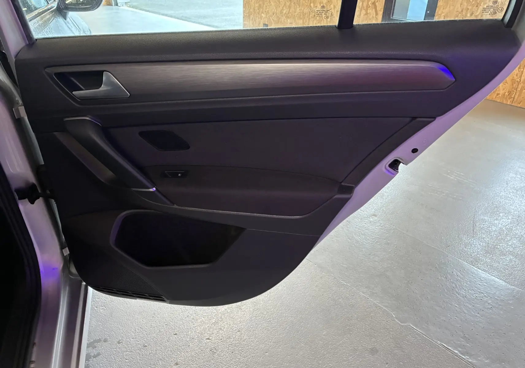 Vue intérieure côté gauche de la porte arrière grise d'une Volkswagen Golf Sportsvan 2019 avec garniture noire et poignée argentée.