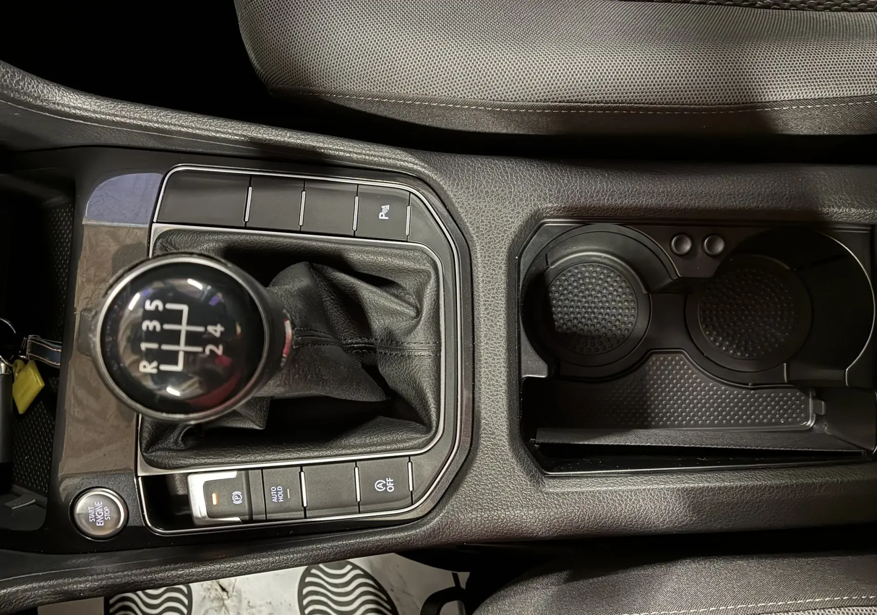 Gros plan sur la console centrale de la Volkswagen Golf Sportsvan grise, mettant en valeur le levier de vitesse manuel et les porte-gobelets.