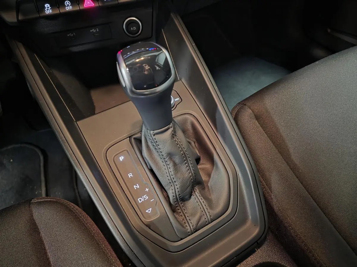 Gros plan sur la console centrale de l'Audi A1 Sportback 2024, levier de boîte automatique en cuir noir.