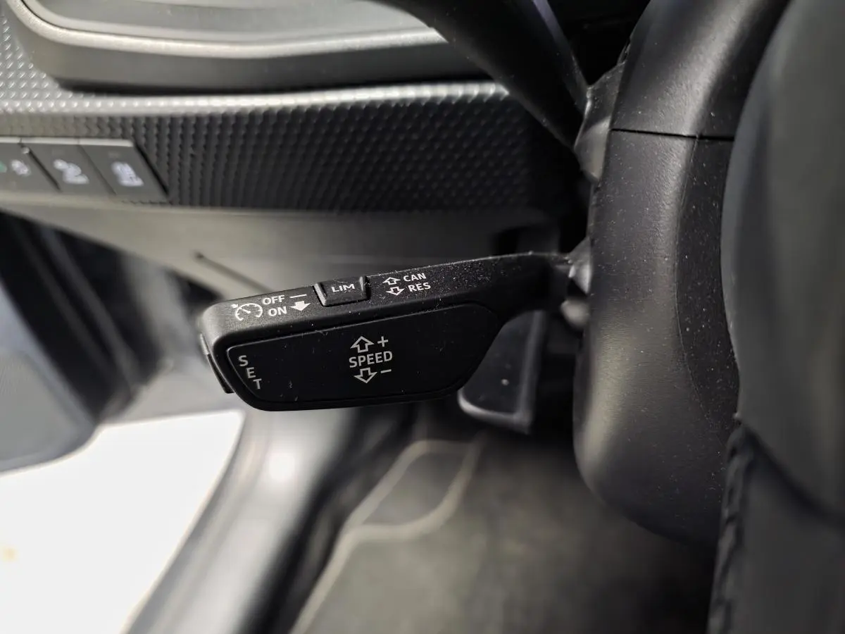 Gros plan sur la commande de régulateur de vitesse au volant cuir de l'Audi A1 Sportback gris 2024.