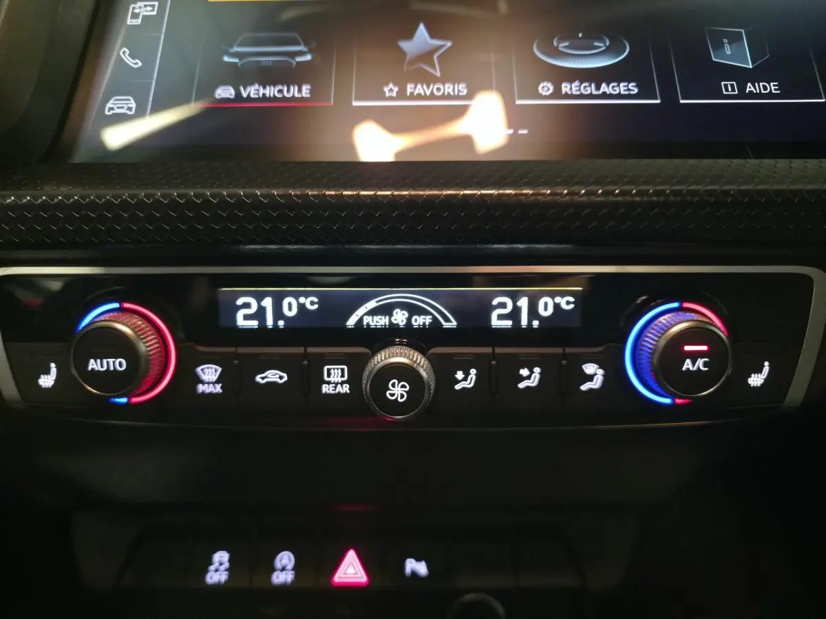 Gros plan sur la console de climatisation automatique double zone de l'Audi A1 Sportback 2024 avec réglages numériques à 21°C.