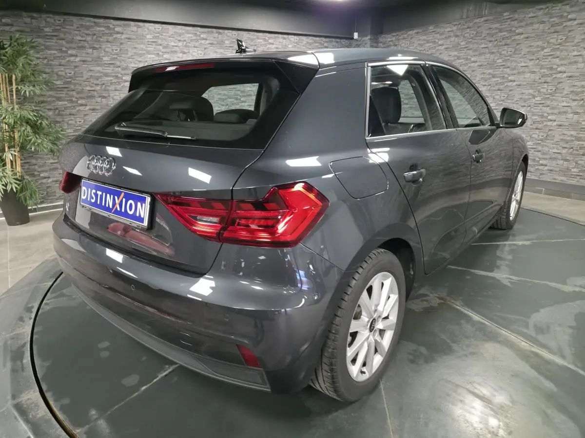 Audi A1 Sportback gris Manhattan vue 3/4 arrière droit en intérieur avec feux arrière LED et jantes argentées.