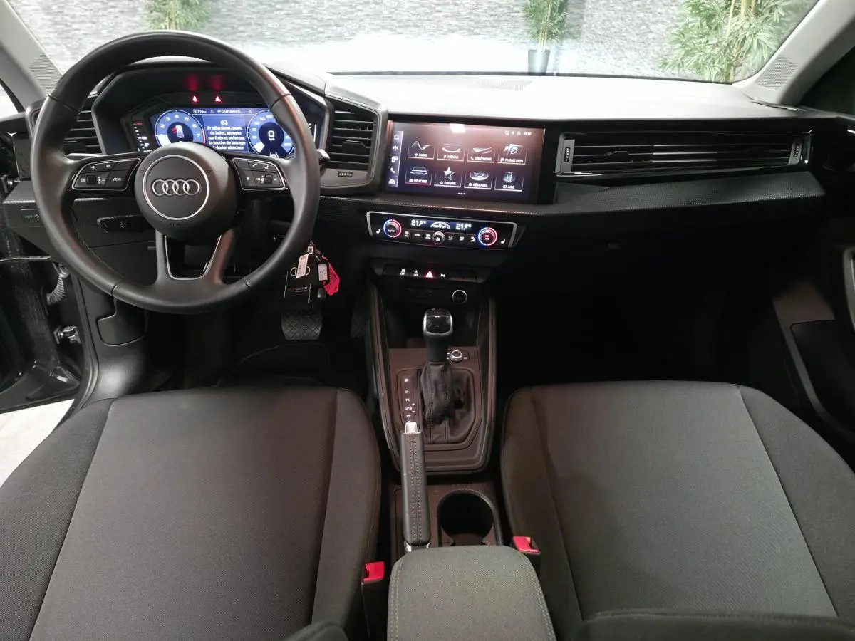 Intérieur avant d'Audi A1 Sportback 2024, vue du conducteur, sièges tissu gris et tableau de bord numérique.