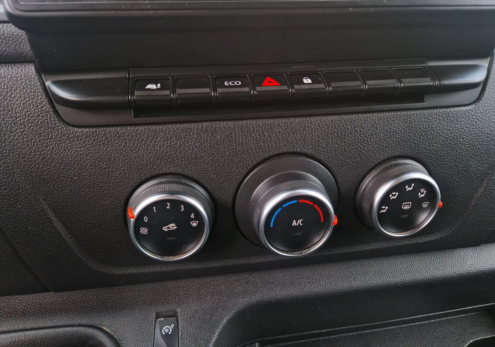 Gros plan sur les commandes de climatisation et boutons de fonction du tableau de bord noir du Renault Master blanc 2020.