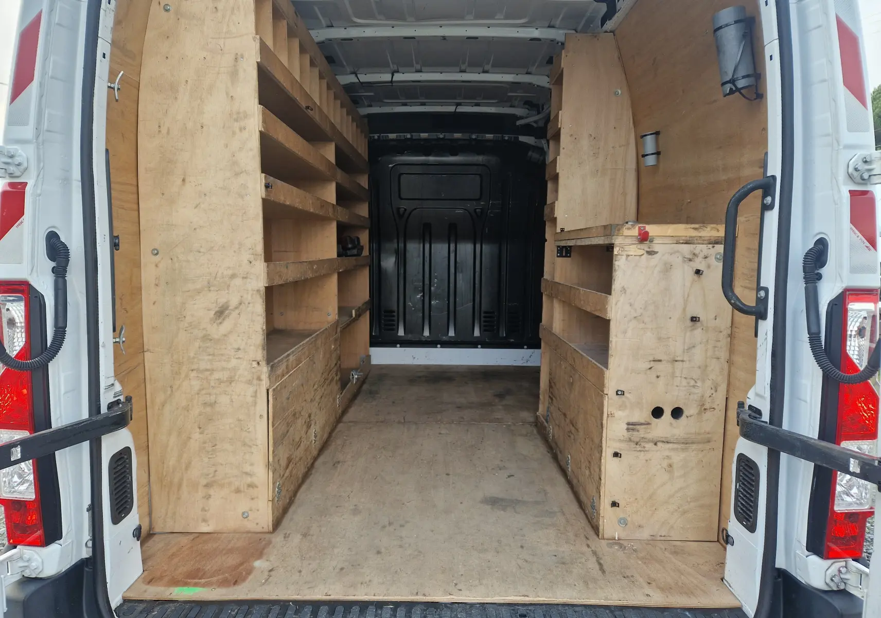 Vue arrière intérieure du Renault Master blanc 2020 avec aménagements en bois et étagères intégrées.
