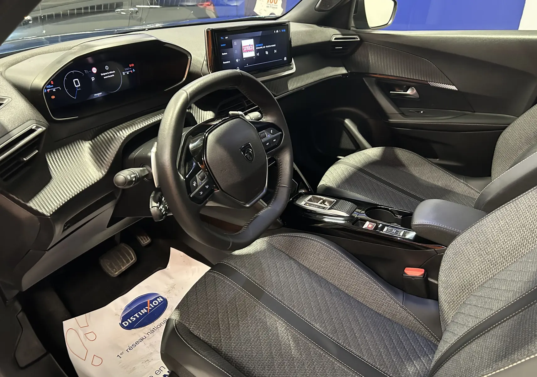 Vue intérieure côté conducteur du Peugeot 2008 Allure Hybrid 145, avec tableau de bord numérique et sellerie tissu gris.