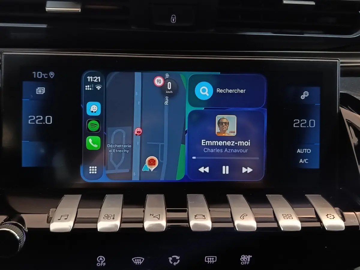 Écran tactile central du Peugeot 508 gris clair de 2020 affichant navigation et musique, avec commandes piano en dessous.