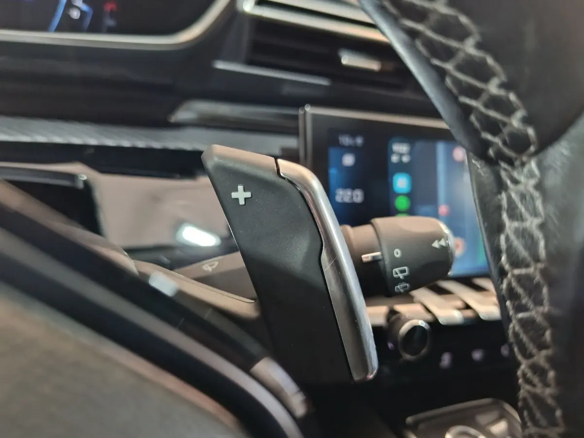 Gros plan sur la commande de palette de changement de vitesse droite dans l’habitacle noir du Peugeot 508 gris clair.