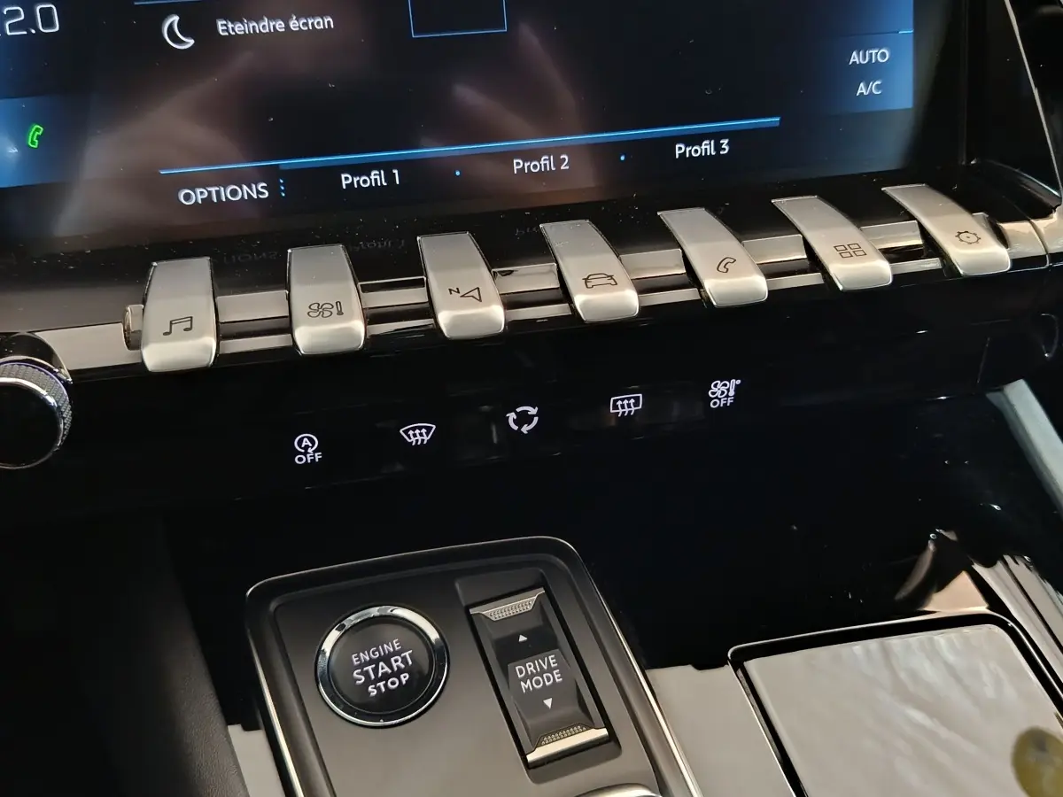 Gros plan sur la console centrale noire du Peugeot 508 gris clair, avec boutons de commande et bouton démarrage visible.