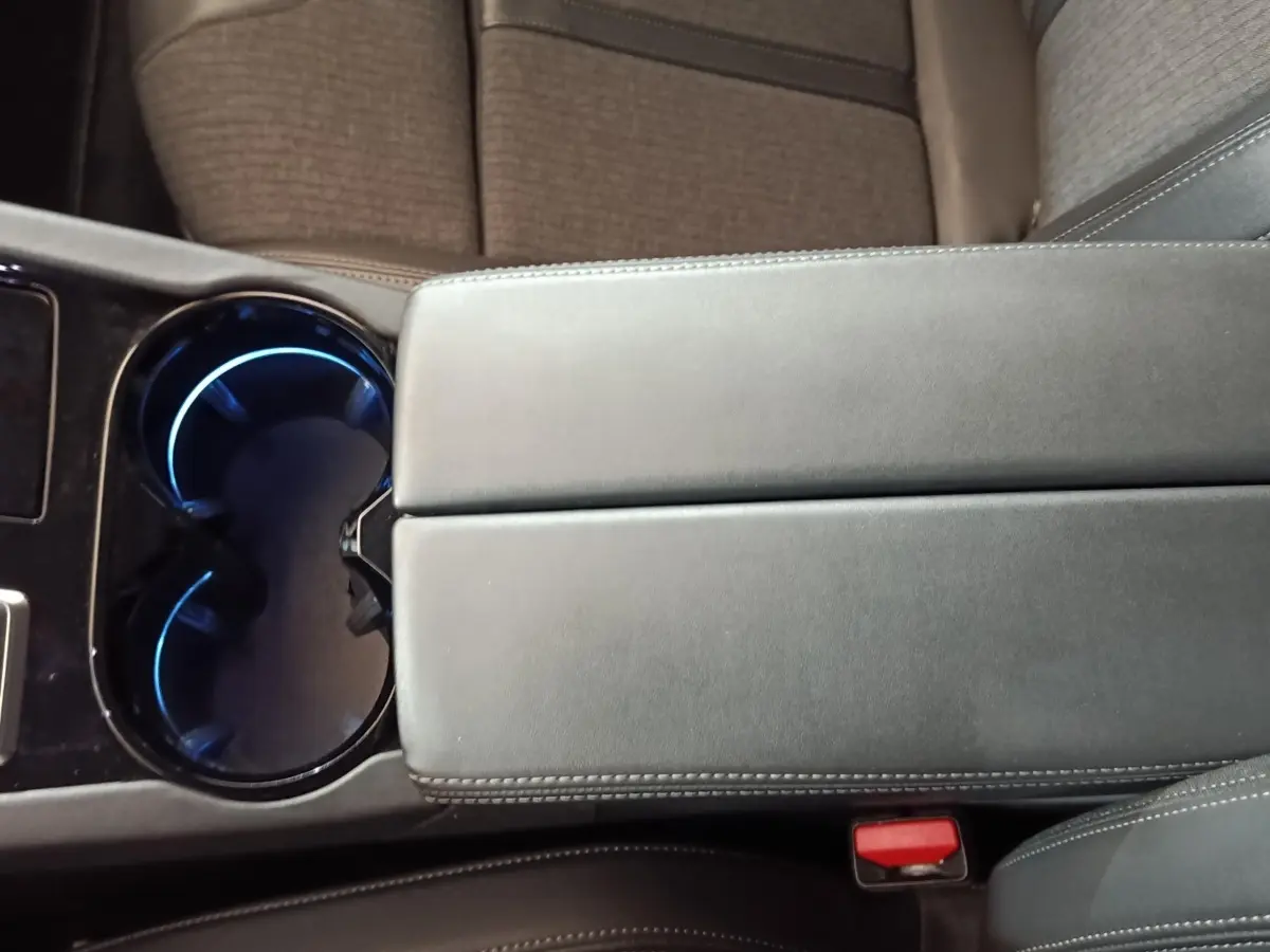 Gros plan sur la console centrale grise avec accoudoir et porte-gobelets éclairé à l’intérieur d’une Peugeot 508 2020.