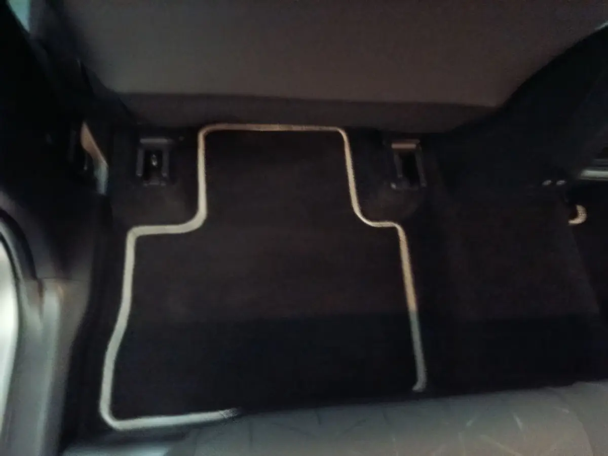 Plancher arrière avec tapis noir bordé de beige dans un Toyota RAV4 Hybride 2WD 218ch, vue centrée au sol.