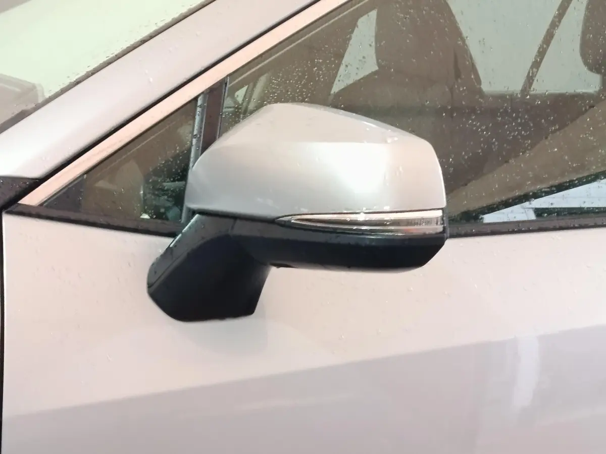 Rétroviseur droit blanc du Toyota RAV4 hybride 2WD 2021, avec clignotant intégré et gouttes de pluie visibles.