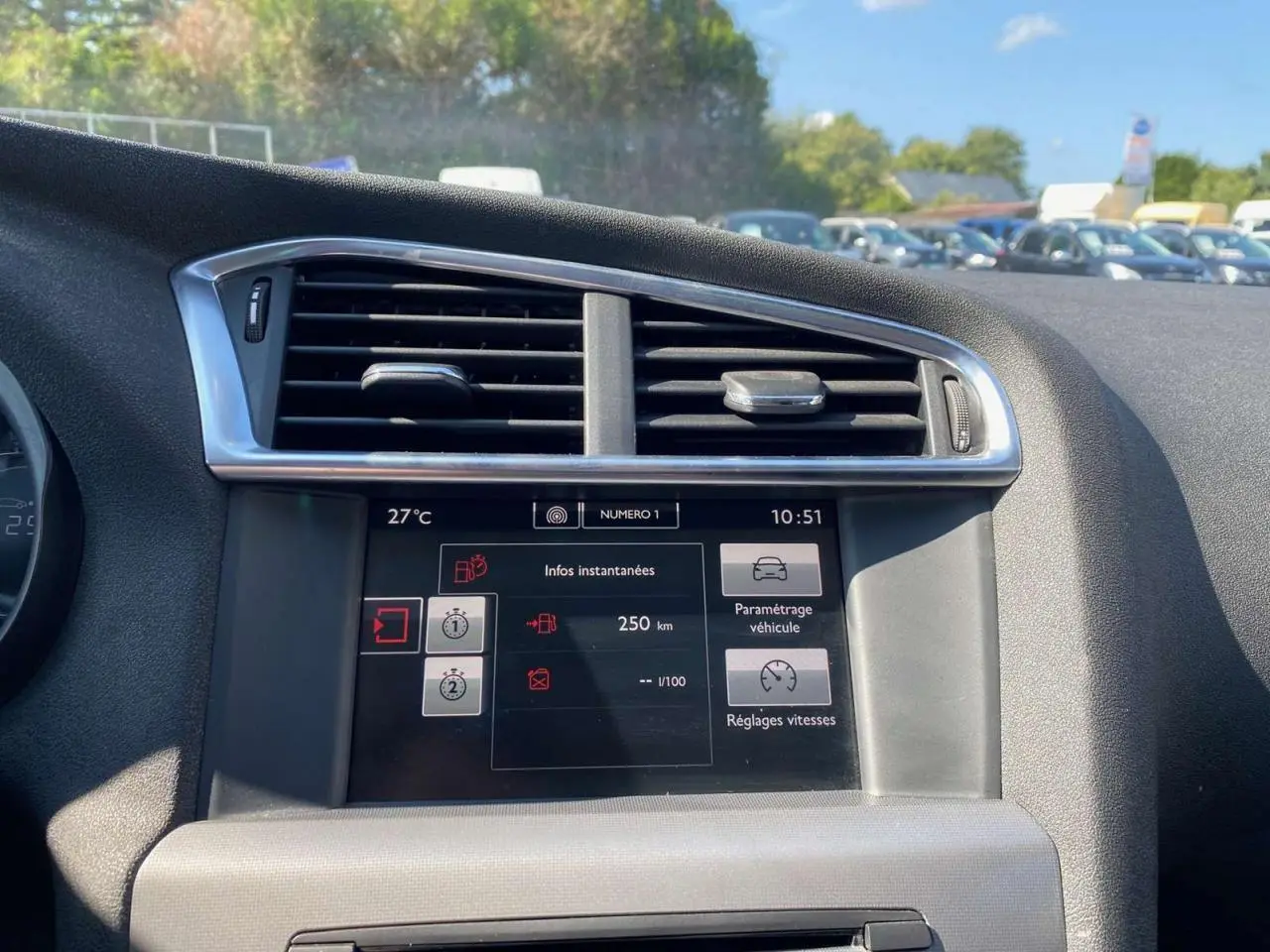 Écran tactile central du tableau de bord d'une Citroën C4 2015, avec commandes de climatisation et réglages affichés.