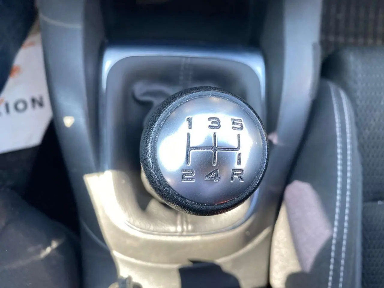 Le levier de vitesses manuel en gros plan de la Citroën C4 rouge Millenium de 2015, montrant les rapports 1 à 5 et la marche arrière.