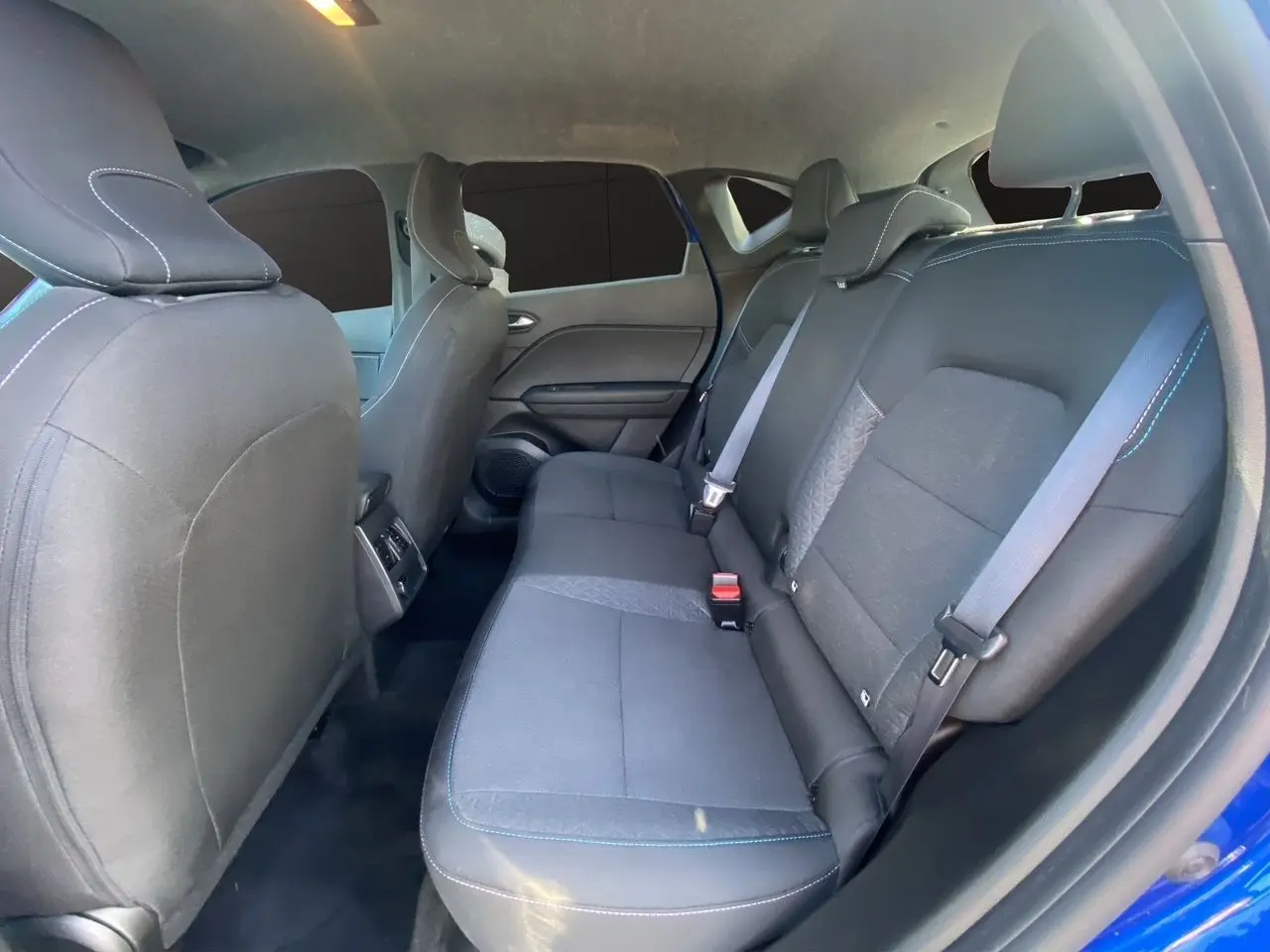 Vue intérieure arrière du Renault Captur 2024 bleu Iron, montrant les sièges arrière en tissu noir avec surpiqûres bleues.