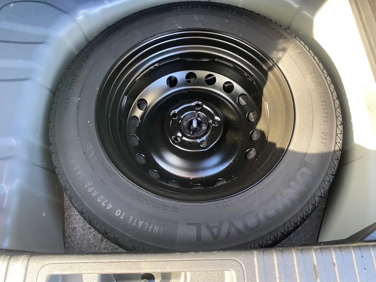 Roue de secours noire en gros plan dans le coffre d'un Renault Captur TCE 90 Evolution bleu iron toit noir 2024.