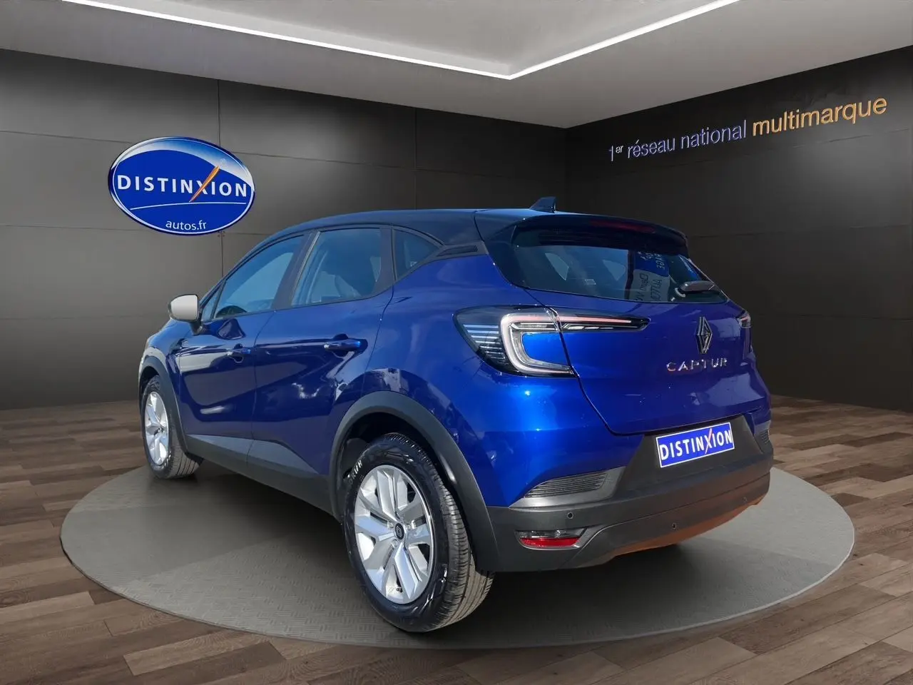 Vue 3/4 arrière droite d'un Renault Captur 2024 bleu Iron à toit noir avec caméra et jantes argentées.