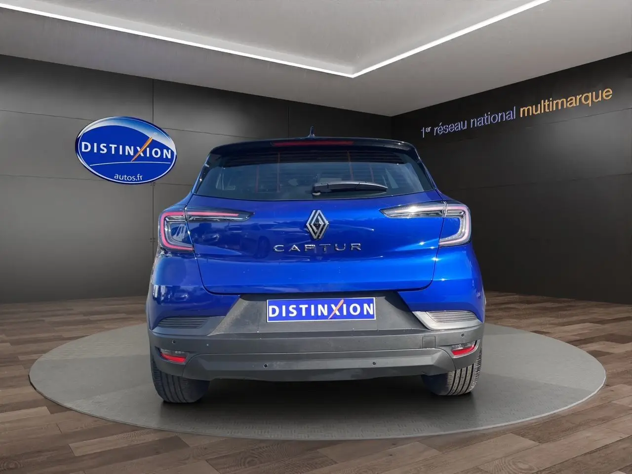 Vue arrière du Renault Captur 2024 bleu Iron avec toit noir et logo distinctif sur fond showroom