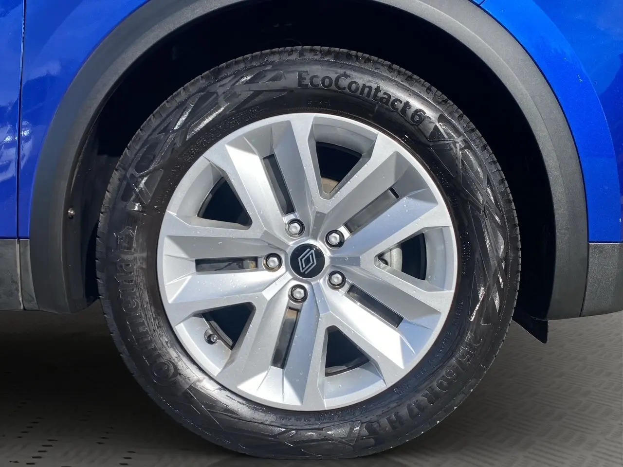 Gros plan sur la roue avant gauche d'un Renault Captur 2024 bleu Iron avec jante argentée et pneus Continental.