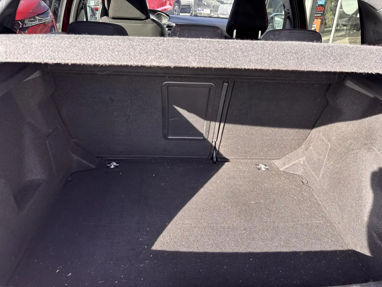 Coffre ouvert de la Peugeot 308 rouge foncé, montrant l'espace de chargement intérieur avec banquette arrière en arrière-plan.