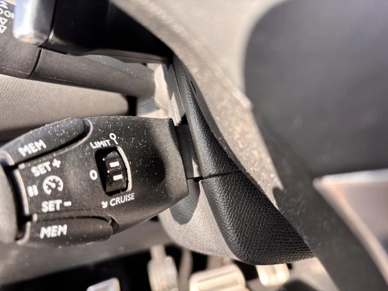 Gros plan sur la commande de régulateur de vitesse au volant d'une Peugeot 308 GT Line rouge foncé de 2016.