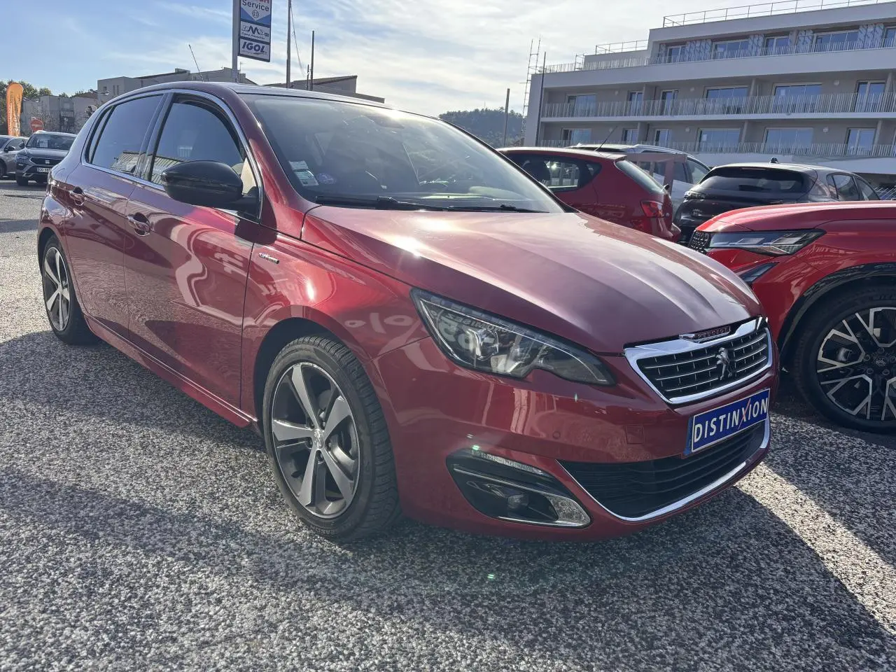 Peugeot 308 GT Line rouge foncé vue 3/4 avant droit avec calandre chromée et jantes diamantées 17 pouces.
