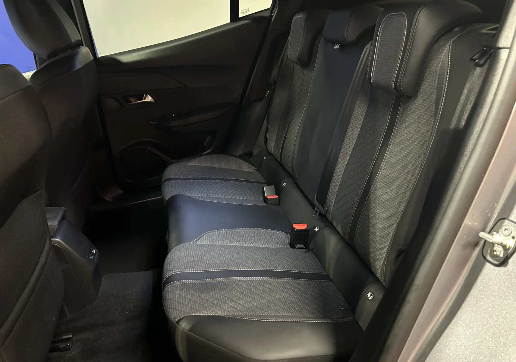 Vue intérieure côté droit des sièges arrière en tissu et cuir noir du Peugeot 2008 Allure Hybrid 2025 gris.