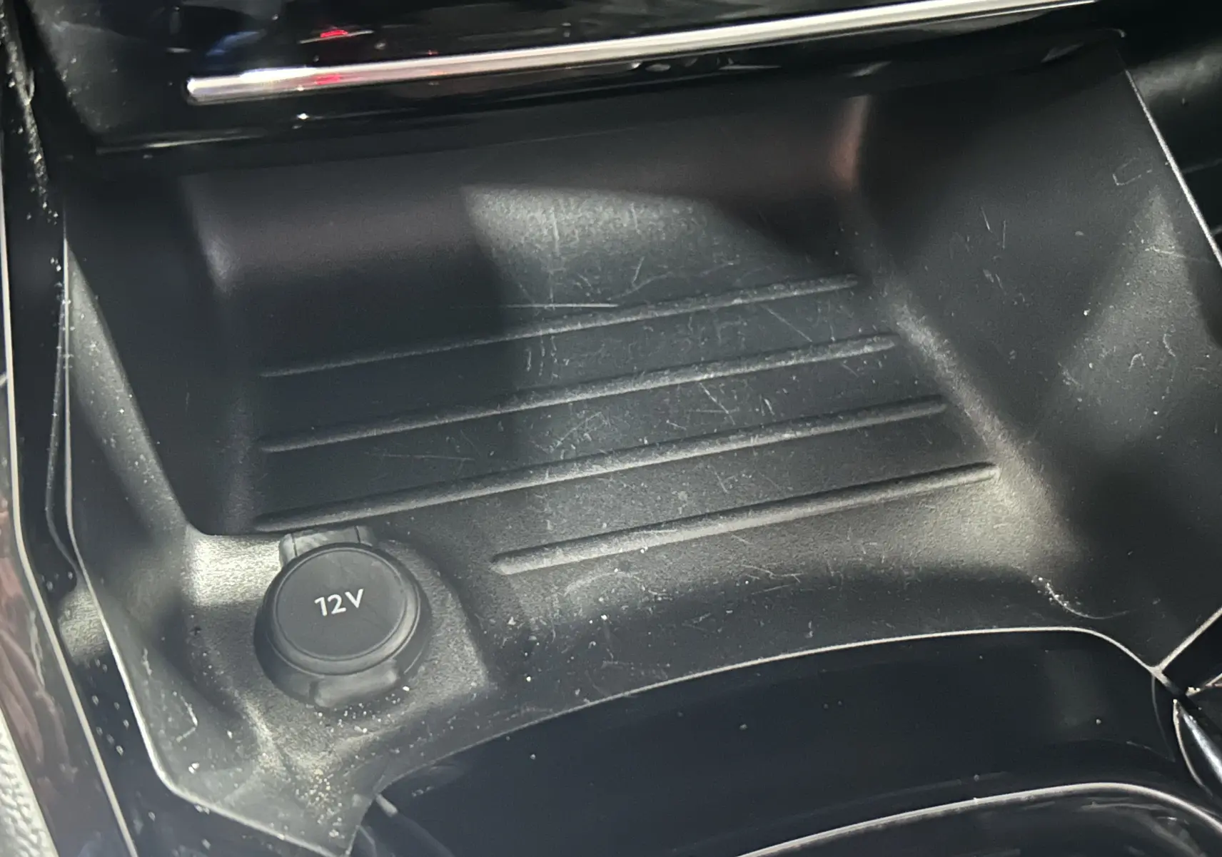 Prise 12V en gros plan dans la console centrale noire du Peugeot 2008 Allure Hybrid 145 e-DSC6 gris 2025.