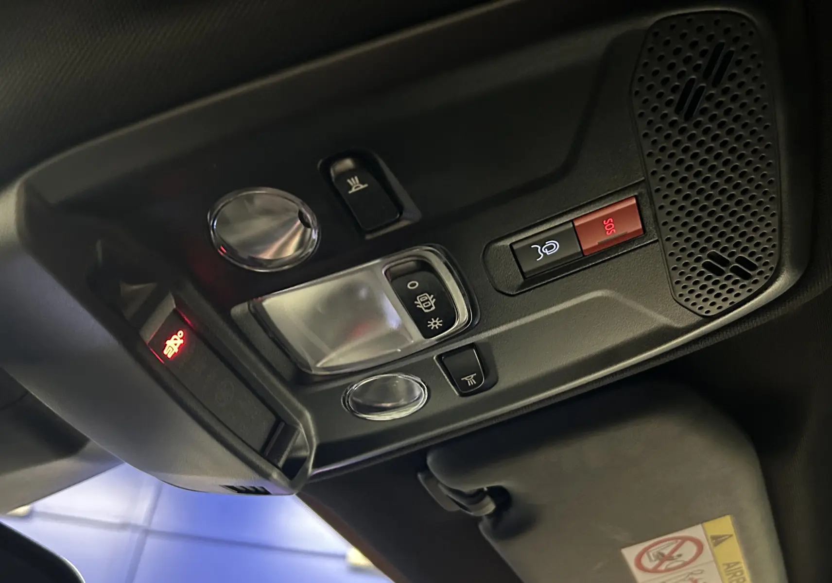 Vue en gros plan du plafonnier intérieur du Peugeot 2008 Allure Hybrid gris, avec commandes d’éclairage et bouton SOS rouge.