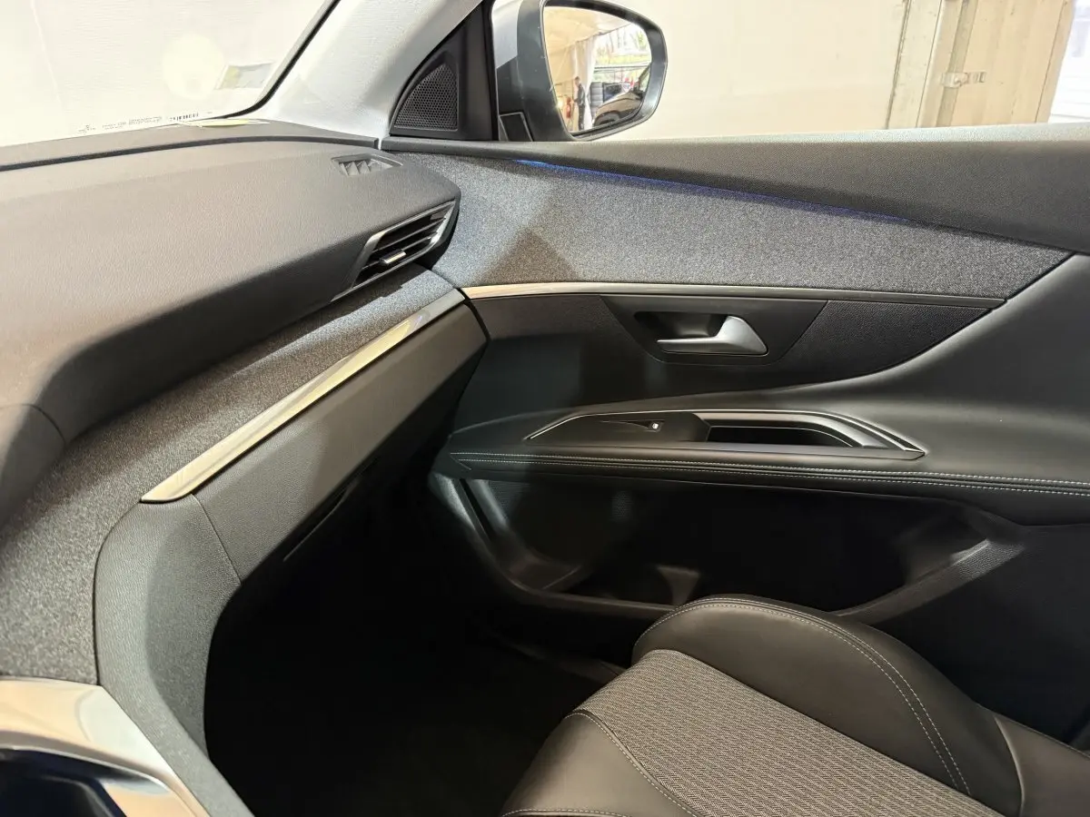 Vue intérieure côté passager du Peugeot 5008 2021 gris clair, montrant la portière et le tableau de bord épuré.