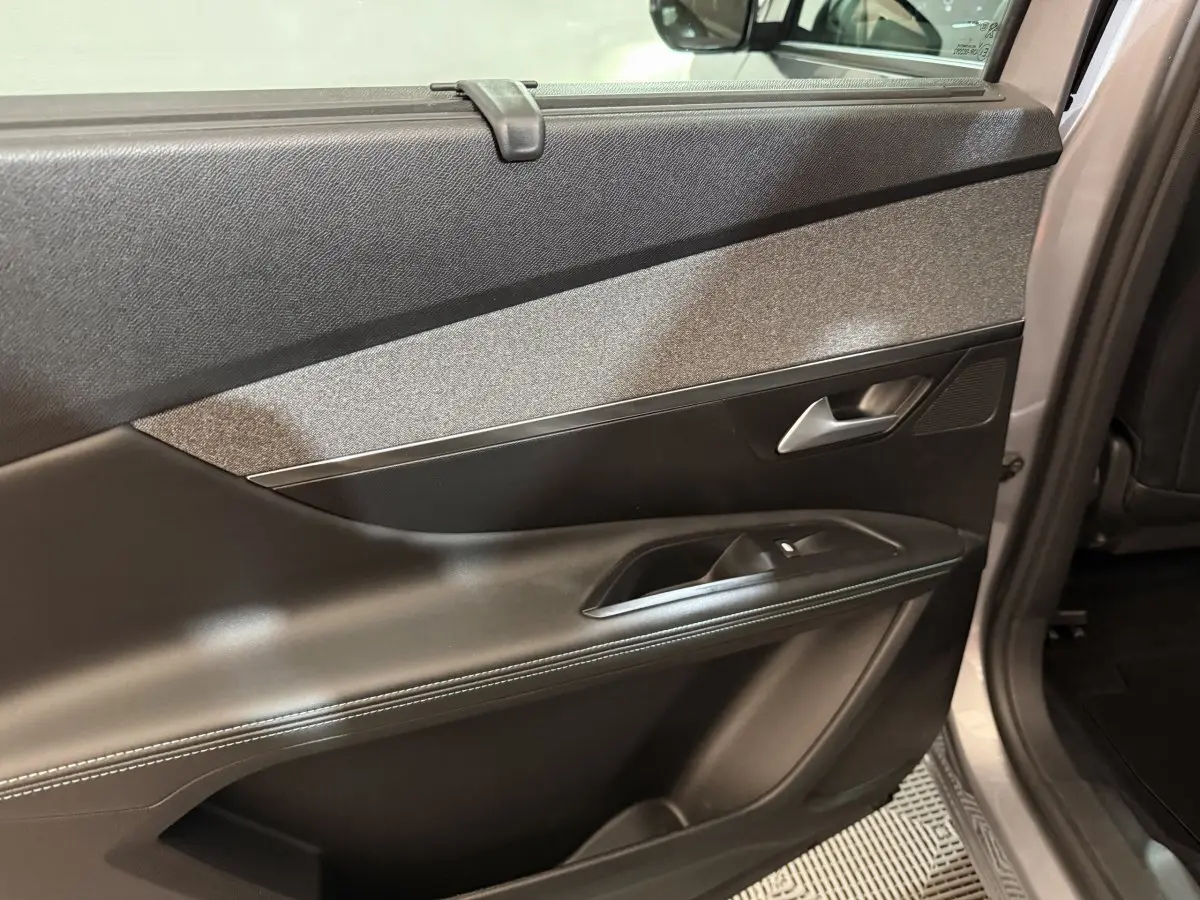 Vue intérieure sur la porte arrière droite du Peugeot 5008 gris clair, avec garniture noire et insert tissu gris.