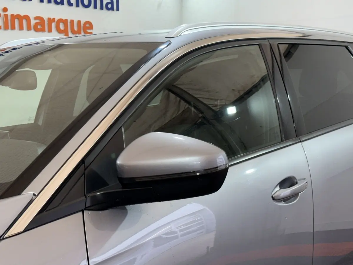 Vue rapprochée du côté gauche d’un Peugeot 5008 gris clair, mettant en valeur le rétroviseur électrique et la poignée de porte.