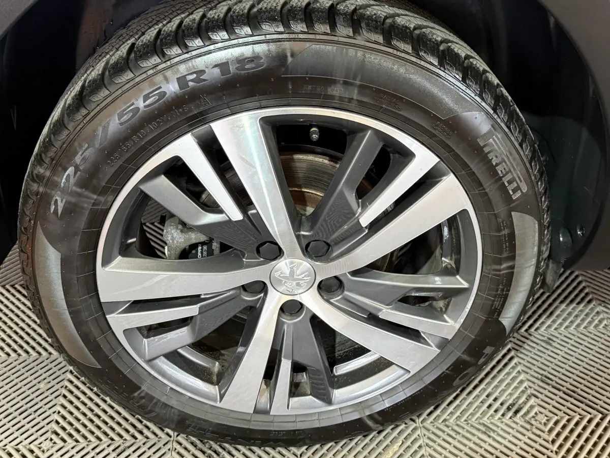 Gros plan sur la jante alliage gris et noir avec logo Peugeot, montée sur pneu Pirelli 225/55 R18.