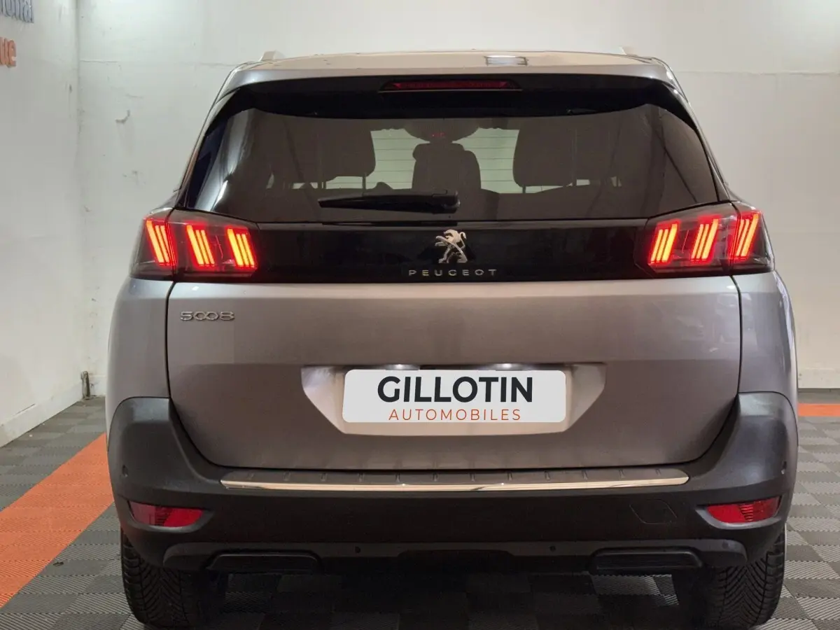 Vue arrière d'un Peugeot 5008 gris clair avec feux LED allumés dans un garage.