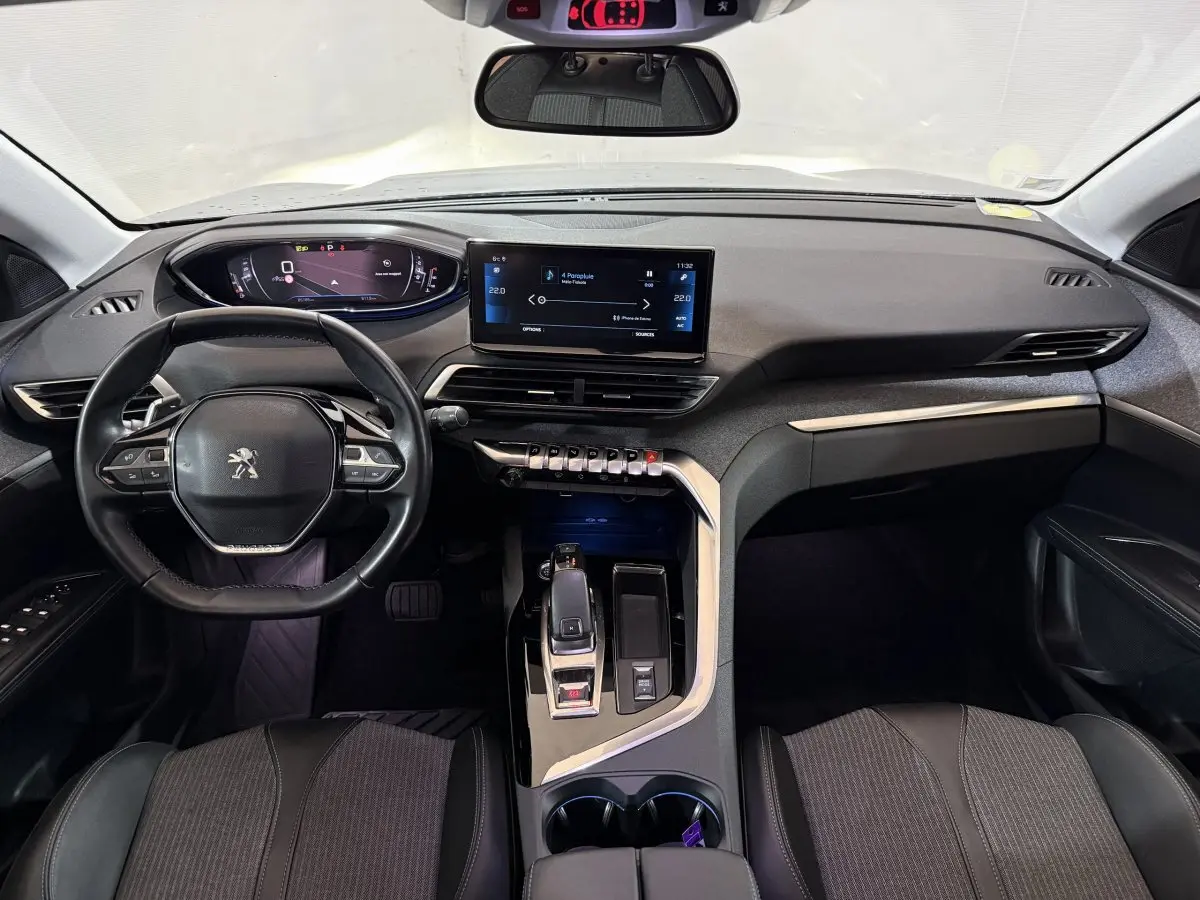 Vue intérieure avant du Peugeot 5008 gris clair 2021, tableau de bord moderne avec écran tactile et volant cuir multifonctions.
