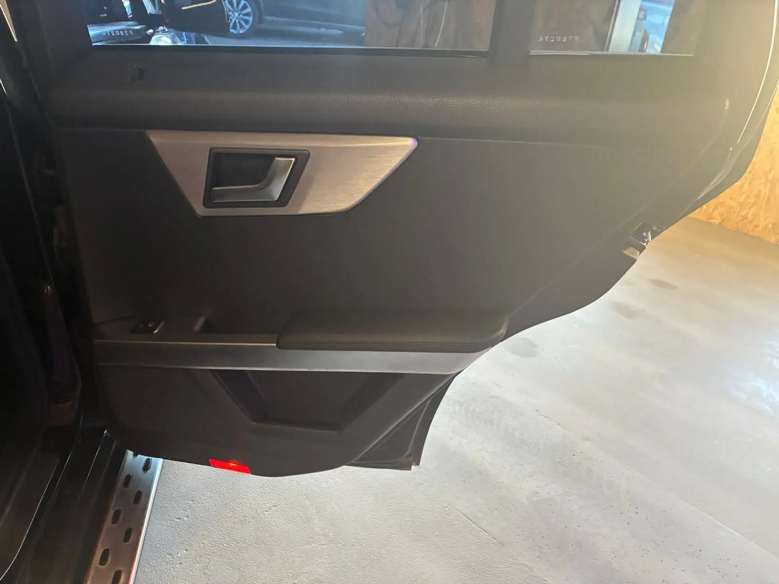 Vue intérieure de la porte arrière gauche noire d'un Mercedes GLK 220 CDI avec poignée argentée et éclairage rouge au bas.