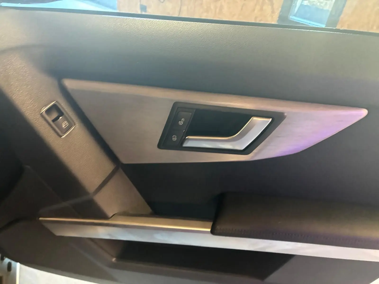 Détail de la poignée de porte intérieure côté gauche du Mercedes GLK noir, avec commande de verrouillage intégrée.