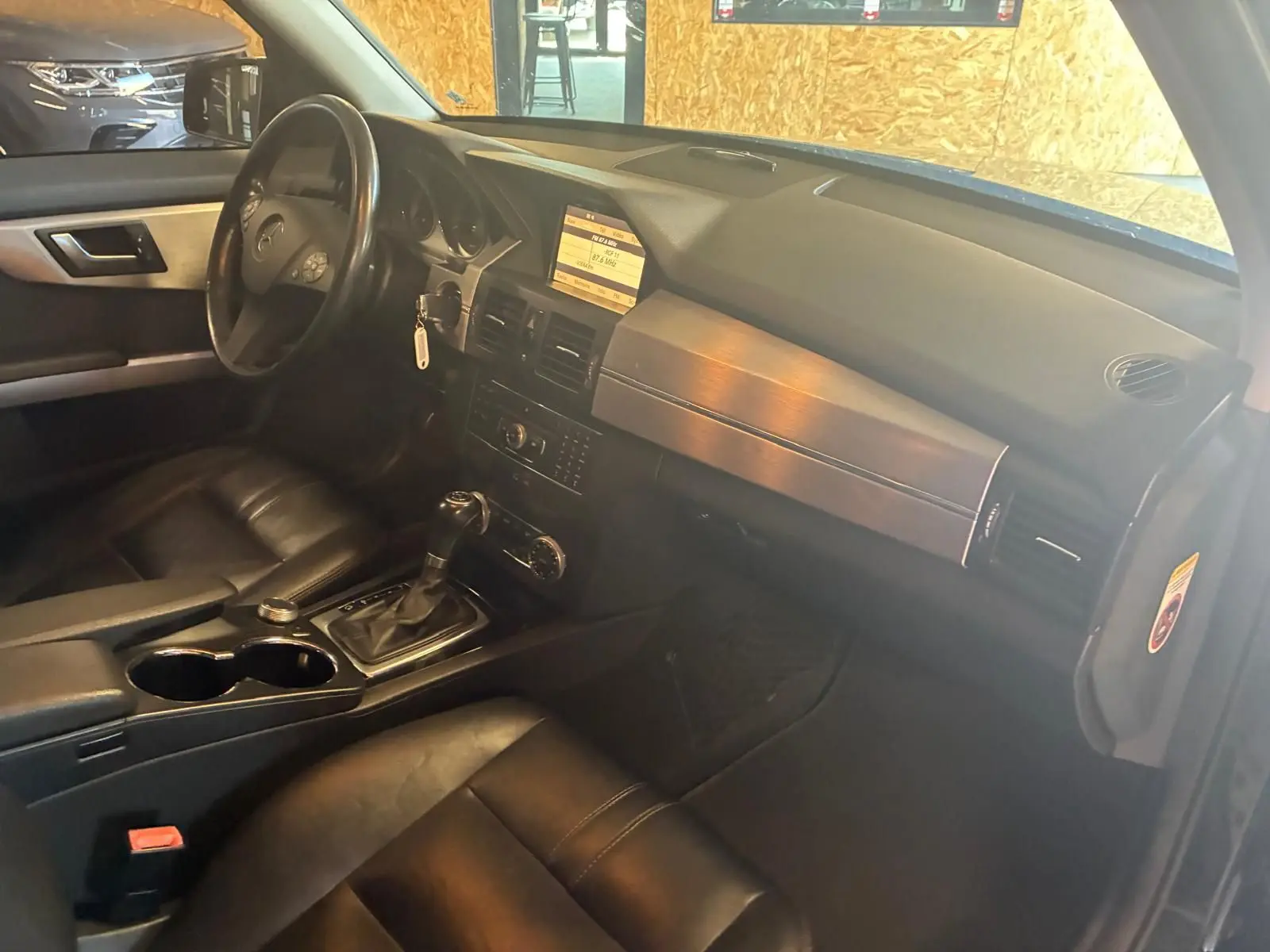 Vue intérieure côté conducteur du Mercedes GLK 220 CDI noir de 2012, avec tableau de bord, volant et console centrale en cuir noir.