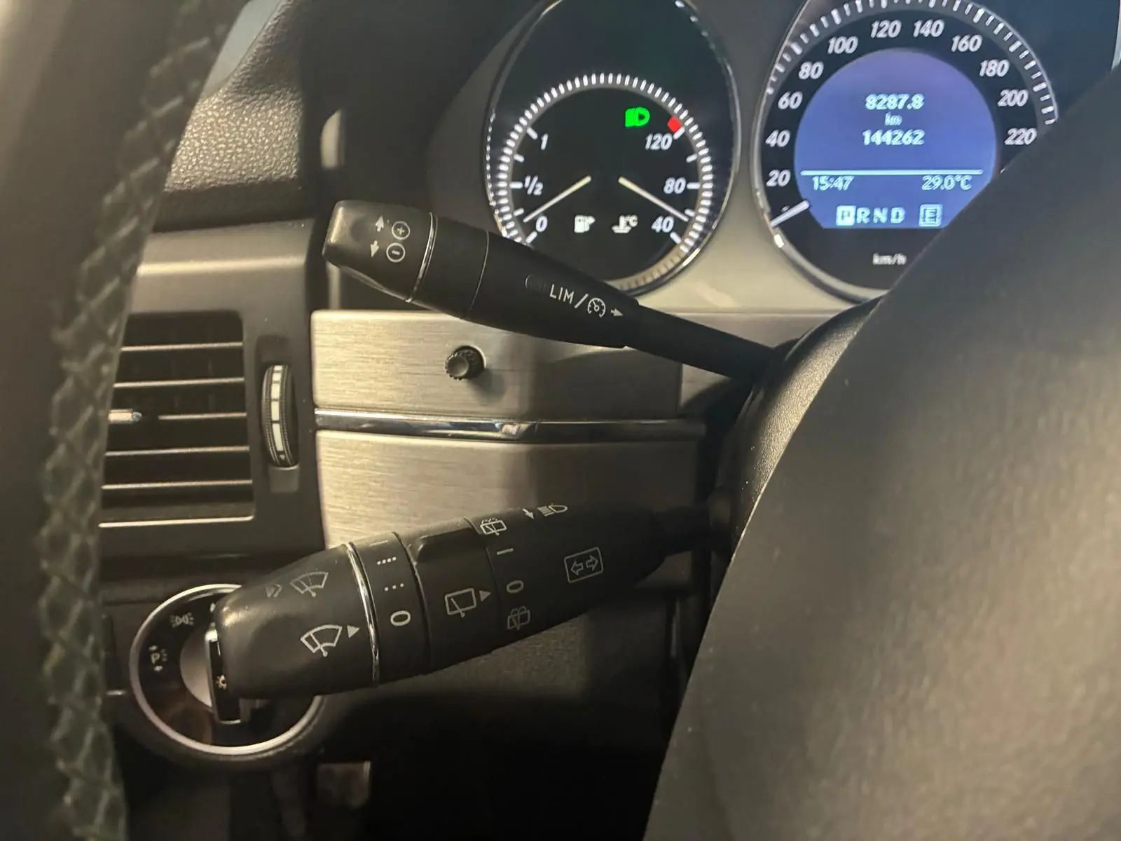 Gros plan sur le tableau de bord du Mercedes GLK 2012, montrant les commandes au volant et les compteurs éclairés.