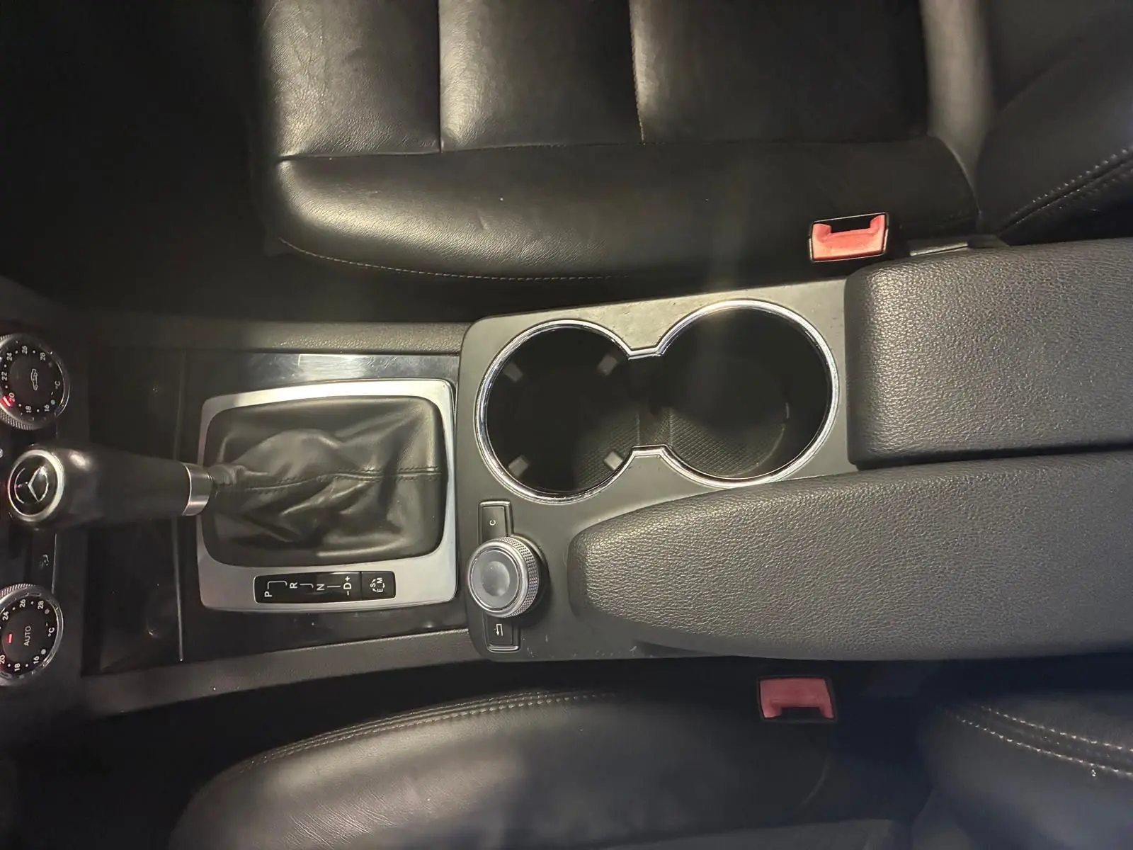 Vue plongeante sur la console centrale noire en cuir du Mercedes GLK 220 CDI avec levier de vitesse automatique et porte-gobelets.