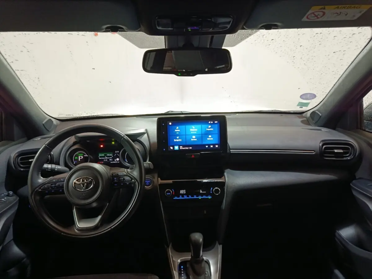Vue intérieure avant du Toyota Yaris Cross gris foncé 2022, avec tableau de bord numérique et écran tactile central allumé.